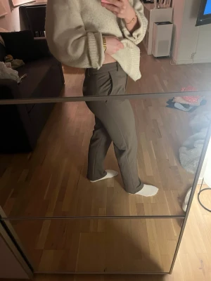 Bruna kostymbyxor  - Snygga bruna kostymbyxor med klassisk rak passform och pressveck. Byxorna har hällor för bälte och stängs med knapp och dragkedja. Perfekta för en stilren och clean look.