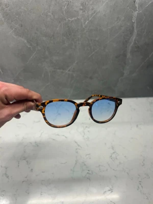 Solglasögon med ljusblått glas - Snygga och trendiga bruna/oranga solglasögon med en klassisk form. De har blåa linser och en stilren design som passar perfekt för soliga dagar. ☀️ En tidlös accessoar för den modemedvetna. Skick 10/10. Priset är inte hugget i sten så skicka gärna prisförslag✅ Skriv vid frågor eller funderingar i DM🍾