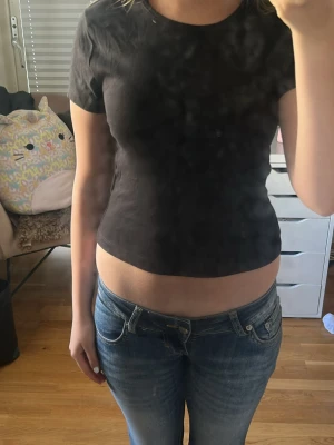 Svart croppad t-shirt - En enkel svart croppad t-shirt med rund halsringning och korta ärmar. Perfekt till jeans eller kjol för en avslappnad och trendig look. T-shirten har en tight passform och är tillverkad i mjuk bomull.