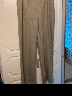 Beiga vida linnebyxor - Snygga beiga linnebyxor med rak och lös passform. Byxorna har hög midja och är tillverkade i ett lätt och luftigt linnematerial, perfekta för en avslappnad och trendig stil.