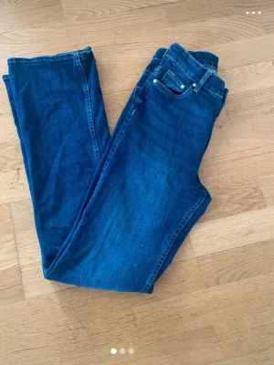 Mörkblå raka jeans - Snygga mörkblå jeans med klassisk femficksmodell och raka ben. Jeansen har normal midja och är tillverkade i ett mjukt denimtyg som ger en skön passform. Perfekta för en avslappnad och stilren look.