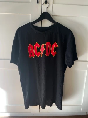 Svart t-shirt från AC⚡️DC - Snygg svart t-shirt från det kända bandet AC⚡️DC. Tishan köptes för cirka 3 veckor sen inför en fest och bara använts en gång. Hör av er kring frågor!