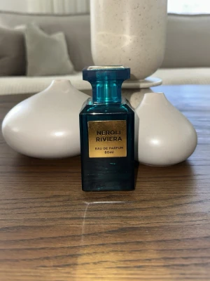 Neroli Riviera Eau de Parfum 80ml - Fräsch parfym i en snygg, blå glasflaska med guldlabel. Flaskan rymmer 80 ml och har en modern, fyrkantig design. Perfekt för dig som gillar exklusiva dofter och vill ha en stilren flaska på hyllan.