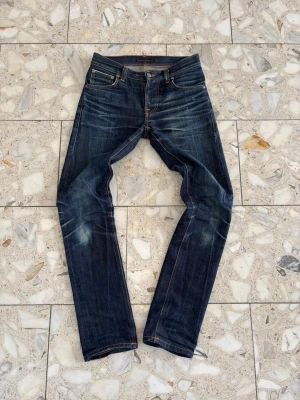 Mörkblå Nudie Jeans - Snygga mörkblå jeans från Nudie Jeans, W:28, L 32, sitter extremt bra, fraktar samma dag📦skick 10/10, det är även selvedge jeans, tveka inte på att höra av er vid frågor eller intressen! Modell: Grim tim