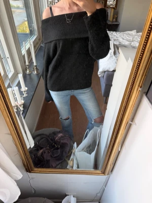 Svart off shoulder stickad tröja💝 - Trendig svart stickad tröja med off shoulder-design och långa ärmar. Tröjan har en bred krage som vilar över axlarna och är gjord i mjukt, mysigt material. Perfekt för dig som vill ha en avslappnad men ändå snygg look samtidigt!