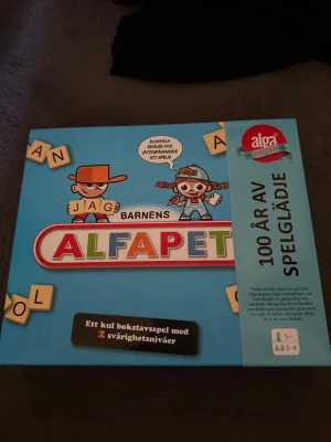 Barnens Alfapet sällskapsspel - Barnens Alfapet är ett färgglatt bokstavsspel från Alga med blå kartong och roliga illustrationer. Spelet har två svårighetsnivåer och passar 2-4 spelare från 5 år. Perfekt för att lära sig bokstäver och ord på ett lekfullt sätt.