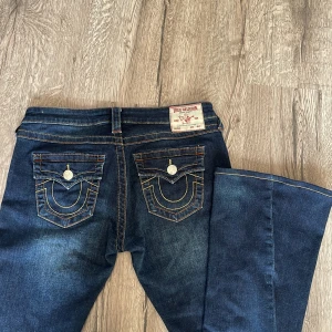 Mörkblå jeans från True Religion - Säljer dessa jätte fina jeans från true religion. köpte de tidigare här på plick men de kommer ej till användning. De har detaljerade fickor och är utsvängda. Innebens längd 78cm och inga skador alls längst ner💕💕