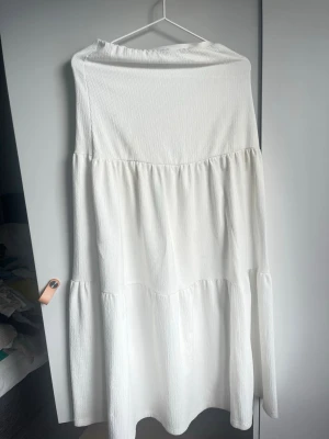 Vit långkjol med volang - Lång, luftig vit kjol i bomull med volangdetaljer och lätt strukturerad yta. Kjolen har en avslappnad passform och är perfekt för sommardagar. Enkel att matcha med olika toppar för en fräsch look. Man ser på bilder små fläckar, inget som jag har märkt tills nu när jag skulle ladda upp, men så att ni är medvetna.