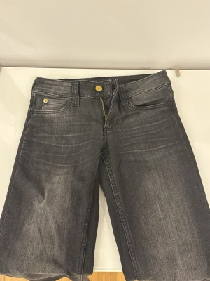 Grå tvättade jeans från Weekday - Snygga grå jeans från Weekday med tvättad look och raka ben. Klassisk femficksmodell med guldfärgade detaljer på knappar och nitar. Jeansen har normal midja och är tillverkade i denim med en cool, sliten finish.