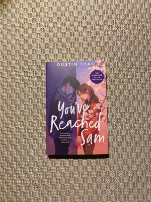 You've Reached Sam av Dustin Thao - En ungdomsroman på engelska med färgstarkt omslag i blått och rosa. Boken handlar om Julie som får kontakt med sin bortgångne pojkvän Sam via telefon. Perfekt för dig som gillar känslosamma berättelser om kärlek och förlust.