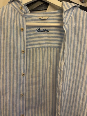 Randig linneskjorta från Stenströms - Säljer en ljusblå och vit randig skjorta från Stenströms i svalt linne. Skjortan har klassisk krage, knappar framtill och broderad logga på ärmen. Perfekt för sommarens alla tillfällen och ger en fräsch look. Size M