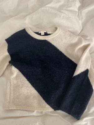 Stickad tröja Gina Tricot svart/vit - Säljer en stickad tröja från Gina Tricot i storlek 158/164. Tröjan är vit med en bred diagonal svart rand över bröstet och ena ärmen. Rund halsringning och mjukt material som känns skönt mot huden. Perfekt för dig som gillar enkel men snygg design.