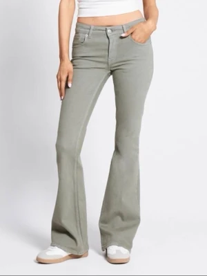 Gröna lågmidjade jeans från 157 - Snygga gröna lågmidjade jeans från 157 med klassisk femficksmodell. Jeansen har utsvängda ben och stängs med knapp och dragkedja. Perfekta för dig som gillar en retroinspirerad look och vill ha något som sticker ut lite.