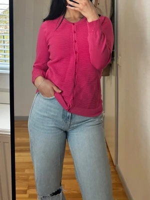 Rosa kofta från Micha - Snygg rosa kofta från Micha med rund halsringning och knäppning framtill. Koftan har ribbad struktur och långa ärmar, perfekt för lager på lager. Enkel och stilren design som passar till mycket. Storlek M men passar även S.