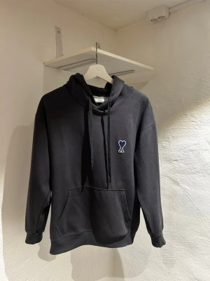 Mörkgrå  hoodie från Ami Paris - Mörkgrå hoodie från Ami Paris. Inga skador eller andra defekter utan är i mycket bra skick. Det är storlek M men skulle säga att den passar S/M. 