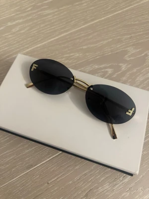 Ovala svarta solglasögon  - Snygga ovala solglasögon  med svarta glas och tunna guldfärgade metallbågar. Klassisk och stilren design som passar till alla outfits. Perfekta för soliga dagar och ger en cool vibe.