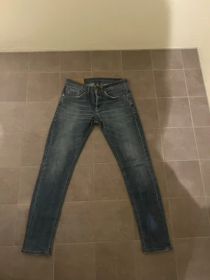 Dondup George W32 - Snygga blå skinny fit jeans med lätt slitna detaljer. Jeansen har normal midja och raka ben, perfekta för en avslappnad och trendig look. Materialet är troligtvis bomull med lite stretch för extra komfort. Hör av dig vid minsta lilla fundering, eller prisförslag.