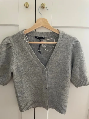 Grå kortärmad kofta Gina Tricot -  Aldrig använd, bara lappen som har åkt av annars är den helt ny och oanvänd!!!                   Nypris 350kr