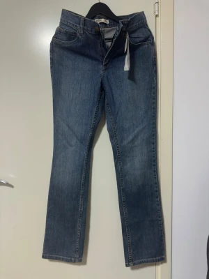 Blå jeans från Ease strl 38 - Snygga blå jeans från Ease med rak passform och klassisk femficksdesign. Jeansen har normal midja och är tillverkade i ett slitstarkt denimtyg. Perfekta för dig som gillar en tidlös och enkel stil.