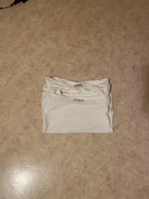 Vit offshoulder t-shirt Gina Tricot - Säljer en vit offshoulder t-shirt. T-shirten har korta ärmar och mudd nedtill. Perfekt för dig som gillar en enkel men trendig stil. Materialet är mjukt och skönt, troligtvis bomull.