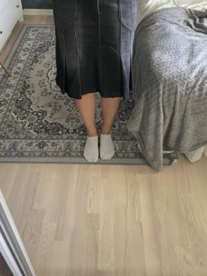 Svart jeanskjol med fickor - Säljer en svart jeanskjol med markerade sömmar och stora fickor fram och bak. Kjolen har knappar som detalj vid fickorna och går till knäna. Perfekt för dig som gillar en enkel men cool stil.