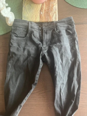 Svarta Replay jeans med smal passform - Snygga svarta jeans från Replay med klassisk femficksdesign och smal passform. Jeansen har Replay-logga på fickan och bak vid linningen. Perfekta för dig som gillar stilrena och bekväma jeans i stretchigt material.