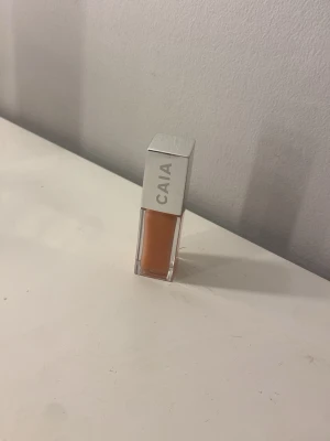 CAIA Juicy Lip Oil  - Juicy Lip Oil från CAIA i en snygg ljusrosa nyans, ser mer persikofärgad ut på kameran. Kommer i en stilren fyrkantig förpackning med silvrigt lock och transparent flaska som visar färgen. Oljan ger glans och återfuktar läpparna med en lätt känsla. Endast swatched på en ren hand