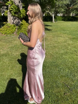 satin rosa Balklänning  - Säljer min ljusrosa/ puderrosa balklänning i satin som är köpt på Nelly men från märket True Decadence! Jag är 165 lång och på bilderna har jag normal höga klackar så den släpar lite i marken, men klänningen har inga synliga defekter av det. Snörena i ryggen är justerbara och kan knytas hur man vill. Den har en fin slips på vänster ben. Klänningen är använd 2 gånger men fortfarande superfint skick!💗