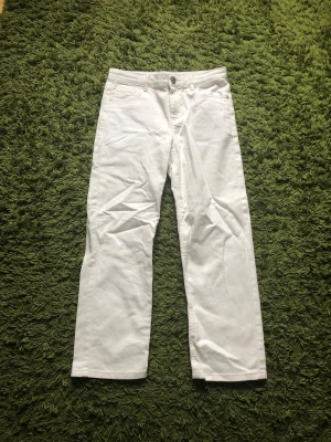Vita raka jeans med fyra fickor - Säljer ett par vita jeans med rak passform och klassisk femficksdesign. Jeansen har bälteshällor, knappgylf och är tillverkade i ett mjukt bomullsmaterial. Perfekta för dig som vill ha en clean och stilren look.