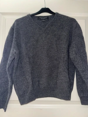 Grå V-ringad stickad tröja - Grå sweatshirt från Bloomingdales. Stroke L, men passar mer en xs, s. Bra skick. Mörk grå färg.