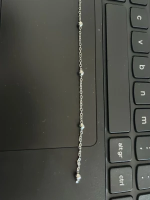 Silverfärgat armband med små pärlor - Ett tunt och stilrent armband i silverfärg med små, runda pärlor jämnt fördelade längs kedjan. Perfekt för dig som gillar minimalistiska smycken med en touch av elegans. Passar att bära ensam eller tillsammans med andra armband.