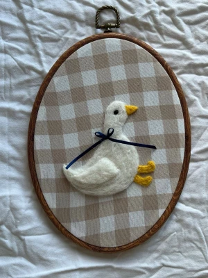 Nåltovad tavla  - Nåltovad tavla i ull med motiv av en anka med rutig bakgrund 🪿❣️   Höjd: 24cm Bredd: 18cmn  Perfekt som dopgåva eller present. Kolla även mina andra annonser 💌