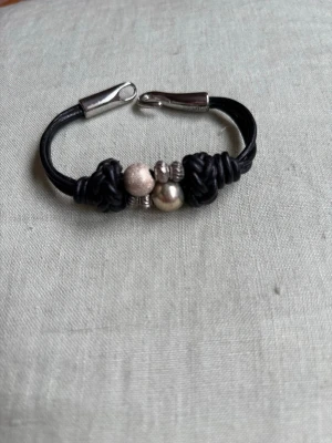 Handgjort läderarmband  - Flätat svart läderarmband med metallpärlor. 19 cm.