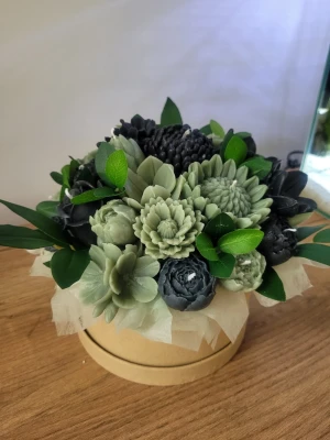 Bukett av handgjorda blomljus - Unik bukett med handgjorda ljus formade som blommor i gröna och mörkblåa nyanser. Ljusen är detaljerade och placerade i en rund ask med dekorativa gröna blad. Perfekt som dekoration eller present till någon speciell. Detta är stl M på boxen
