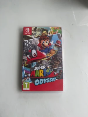 Super Mario Odyssey till Switch - Super Mario Odyssey till Nintendo Switch. Färgglad spelkassett och fodral med Mario och hans röda hatt Cappy på omslaget. Spelet är ett äventyrsspel där du utforskar olika världar och samlar månar. Fodralet är gjort av plast och har tryckt omslag i flera färger.