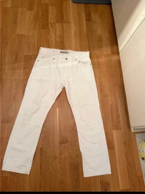 Vita Levi's 506 Standard jeans - Säljer ett par klassiska vita jeans från Levi's, modell 506 Standard. Jeansen har rak passform, fem fickor och är tillverkade i bomull. Perfekta för dig som gillar en clean och tidlös look. Och perfekt för sommaren