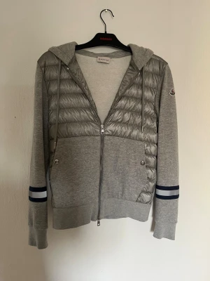 Moncler cardigan  - Säljer nu denna otroligt sällsynta moncler cardigan som det finns väldigt få utav. Färgen är en klar grå färg med snygg detalj vid bröstet. Skick 9/10. Storlek S. För fler frågor eller funderingar är det bara att skriva 