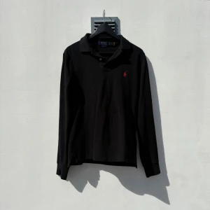 Polo Ralph Lauren Piké - Tja! Svart långärmad piké från Polo Ralph Lauren. Tunn piké som passar perfekt nu till sommaren! (Size: S)  (Skick: 4/5)  (Retail: 1799)  (Vårt pris: 500kr). Hör av er vid frågor & funderingar! /Mvh, Morëtti Co.