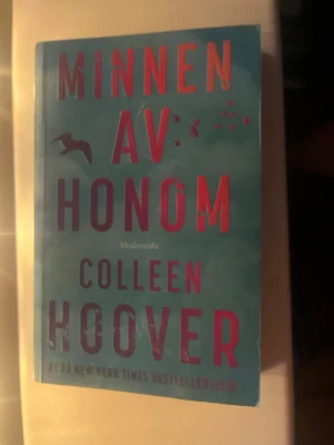 Minnen av honom av Colleen Hoover - En gripande roman av Colleen Hoover med blått omslag och rosa text. Boken handlar om Kenna som försöker återförenas med sin dotter efter ett tragiskt misstag. Perfekt för dig som gillar känslosamma och starka berättelser.
