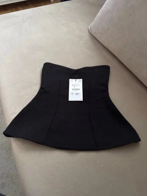 Svart axelbandslös korsett från Zara - Svart axelbandslös korsett från Zara med utsvängd nederkant och figurnära passform. Toppen är helt ny och har prislapp kvar 