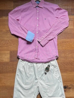 Morris Skjorta Herr Small Rosa/Rutig  -  Snygg rosa/vit morris skjorta med fina ljusblå detaljer vid manschetterna. Perfekt för old money/preppy look och passar lika bra uppklätt som casual. Mycket fräsch och stilren tillsammans med ljusa chinos eller shorts.                                      Kommer från ett rökfritt hem 📦 Snabb frakt 💬 Skriv vid frågor eller paketpris.                  