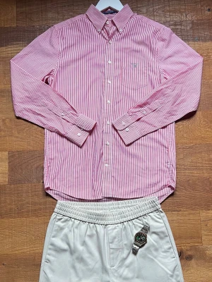 Gant Skjorta Herr Small Rosa/randig  - Snygg rosa/vit randig skjorta som passar perfekt för clean old money fits. Väldigt lätt att styla och ser dyr ut tillsammans med ljusa shorts/chinos.                                             Kommer från ett rökfritt hem.                       📦Snabb leverans                                            Paketpris finns 