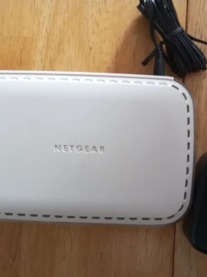 Vit nätverksswitch från Netgear - En vit nätverksswitch från Netgear med åtta portar, perfekt för att koppla ihop flera enheter i hemmet eller på kontoret. Tillverkad i plast med rundade hörn och diskret design. Strömkabel medföljer.