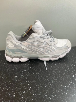 Vita och grå Asics sneakers - Asics skor ej använda, storlek 42 men små i storlek . Skokartong finns med. 