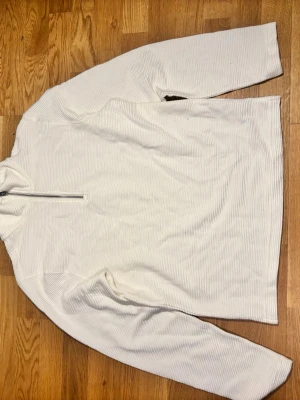 Ribbstickad Half-Zip Tröja från H&M  - Snygg och stilren ribbstickad tröja från H&M med half-zip krage. En modern och mångsidig modell i en fräsch off-white nyans som passar perfekt att matcha med jeans eller dressade byxor. 