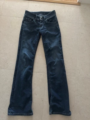 Mellanblå tall  low flared jeans  - Säljer ett par mellanblå low flared jeans från Bikbok. Supersnygga som passar till mycket, snygg detalj på bakfickorna också. Storleken är S och längden är 34. 
