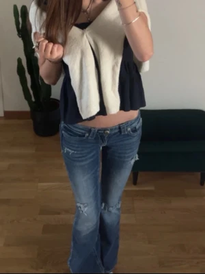 Blå slitna bootcut jeans Gina Tricot - Säljer ett par blå bootcut jeans från Gina Tricot i storlek XS. Jeansen har slitna detaljer, låg midja och klassisk femficksmodell. Perfekta för en avslappnad och trendig look. Materialet är denim med snygg tvätt och dragkedja framtill. Bytat knapp då förra gick av.