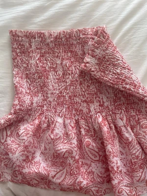 Fin rosa topp med mönster  - Det är en fin topp i bra skick som nästan aldrig användts. Toppen hade förut axelband men inte längre. (Går att sätta dit egna, bild 2)                  Om man vill funka även som kjol 