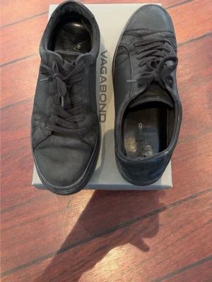 Svarta sneakers från Vagabond - Stilrena helsvarta sneakers från Vagabond med lågt skaft och klassisk snörning. Skorna är tillverkade i slätt läder och har en diskret design som passar till det mesta. Perfekta för dig som gillar minimalistisk och clean stil.