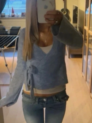 Ljusblå omlottkofta med knytband - Trendig ljusblå omlottkofta med knytband i sidan och v-ringad hals. Koftan har långa ärmar och en mjuk, stickad känsla. använd 4 gånger. går att styla på flera sätt och är perfekt till alla tillfällen. skriv om du har några frågor🤗